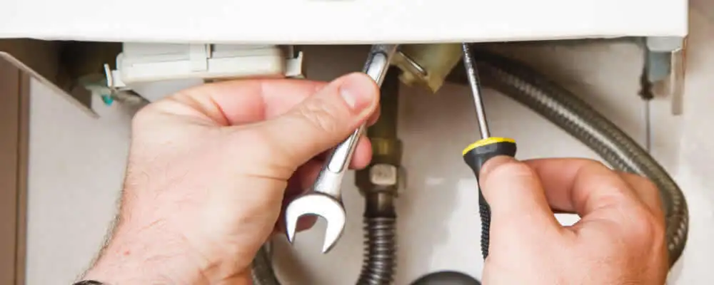 Boiler repair technician tightening pipe fittings and connections in Palm Springs, CA