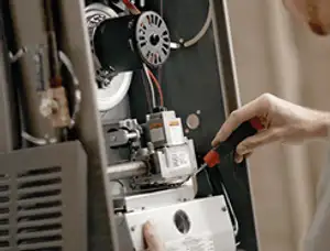 Furnace repair technician inspecting internal components and wiring in Palm Springs, CA
