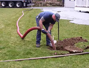 Septic pumping technician servicing a residential septic tank with a vacuum hose in Palm Springs, CA