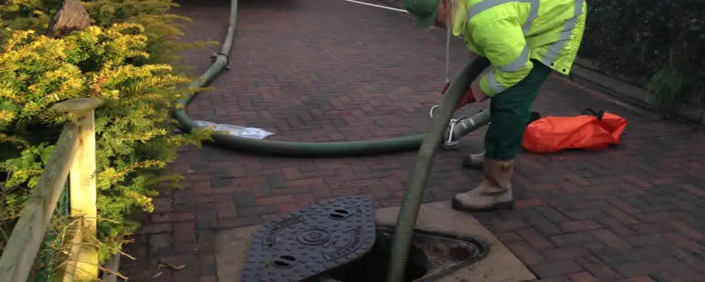 Septic tank cleaning technician servicing a septic tank with a vacuum hose in Palm Springs, CA