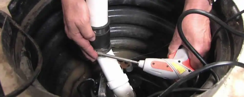 Sump pump installation technician connecting PVC discharge piping in Palm Springs, CA