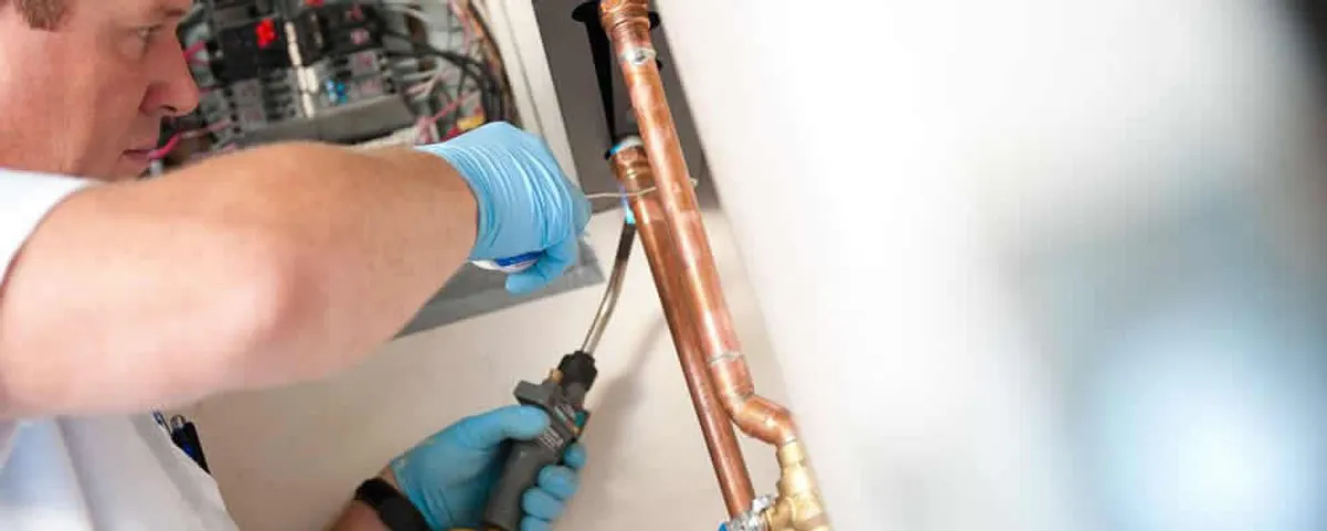Water heater repair technician testing copper pipe connections and controls in Palm Springs, CA